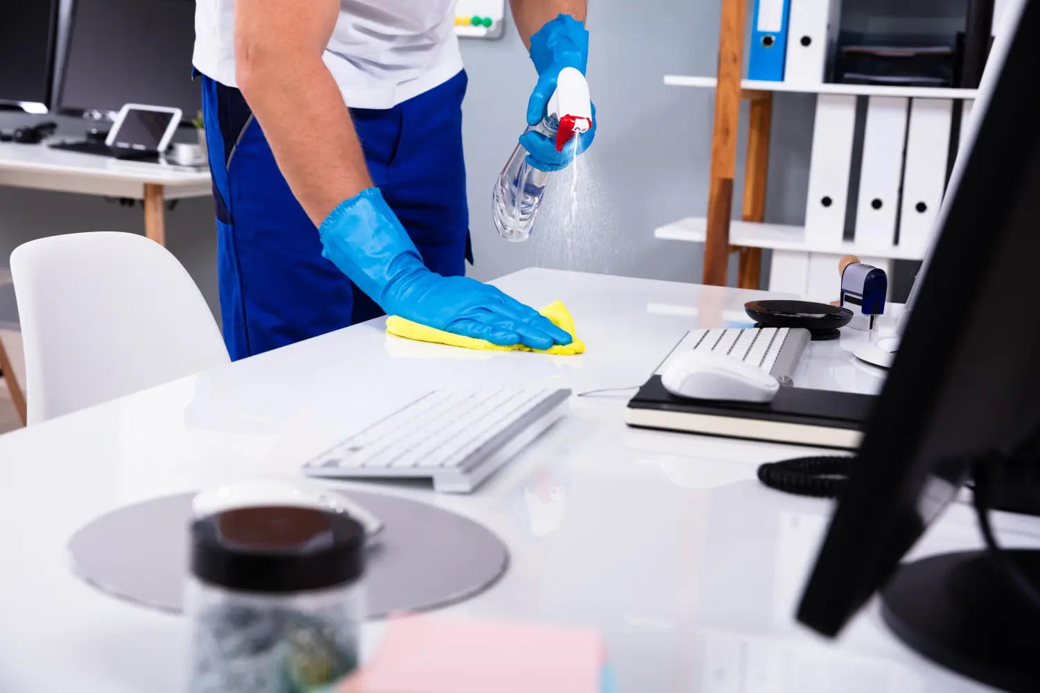 Hausmeister reinigt weißen Schreibtisch im Büro